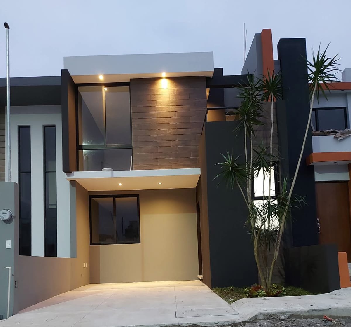 Fachada contemporánea iluminada al anochecer con revestimiento oscuro
